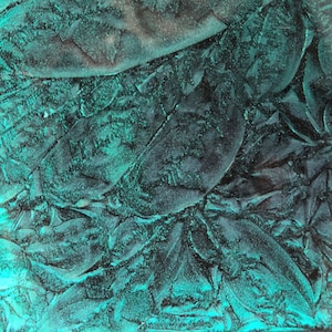May include: A close-up of a textured teal surface with a mottled, almost iridescent, appearance. The surface has a rough, uneven texture.