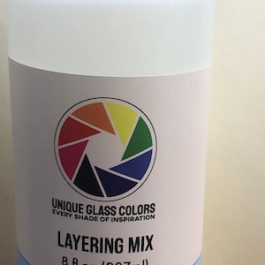 May include: A translucent plastic bottle with a white cap and a label featuring a colorful circular design. The label reads "UNIQUE GLASS COLORS" and "LAYERing MIX", with a volume of 8 fl oz (237ml).
