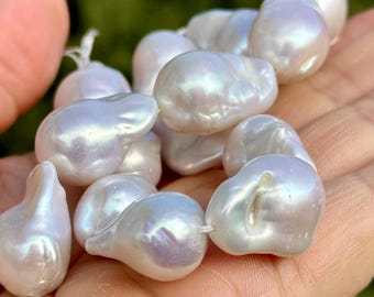 May include: A strand of white baroque pearls with an iridescent sheen. The pearls are irregular in shape and have a smooth, glossy finish.