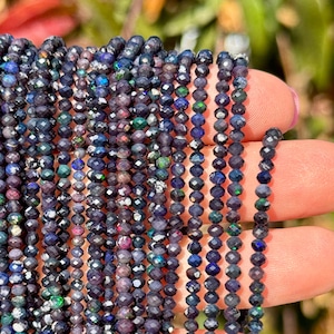 May include: A strand of black opal beads with a faceted finish. The beads are small and have a dark, iridescent sheen.