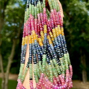 May include: A strand of colorful gemstone beads, including blue, green, yellow, and pink, strung together in a rainbow pattern.