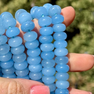 May include: A strand of light blue gemstone beads. The beads are round and have a smooth, polished finish.