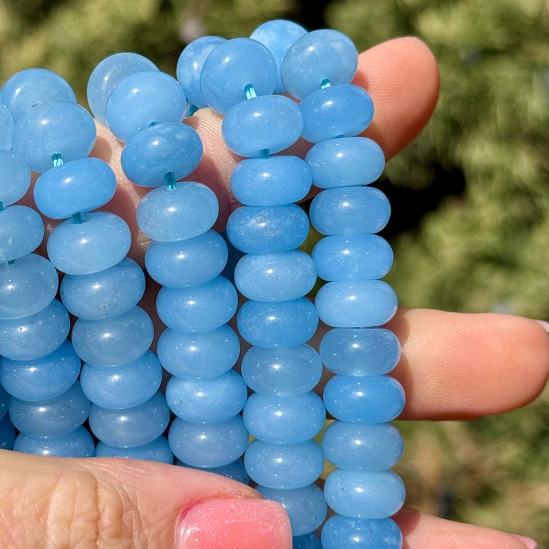 May include: A strand of light blue gemstone beads. The beads are round and have a smooth, polished finish.