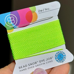 May include: A spool of bright neon green Griffin Bead Snob Dye Job cord. The label features a colorful design with the text "2m/No." and the Griffin logo. The cord is hand-dyed and made in Germany.