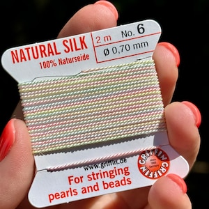 May include: A spool of 2 meters of natural silk thread, 0.70 mm in diameter, for stringing pearls and beads. The spool is labeled "NATURAL SILK 100% Naturseide" and "No. 6".