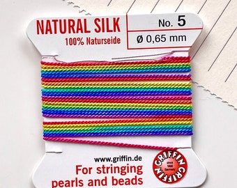 May include: A spool of rainbow coloured natural silk thread for stringing pearls and beads. The spool is labelled "Natural Silk 100% Naturseide No. 5 Ø 0,65 mm" and "For stringing pearls and beads".