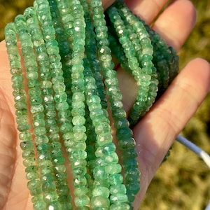 以下が含まれることがあります： エメラルドグリーンの宝石ビーズのストランド。ビーズはファセットカットされており、わずかに不規則な形をしています。ビーズは透明な糸に通されており、直径は約3mmです。