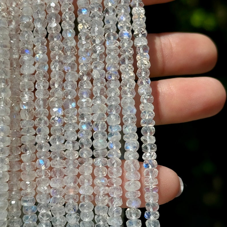 May include: A strand of white moonstone beads with a faceted, teardrop shape. The beads have a subtle iridescent shimmer.