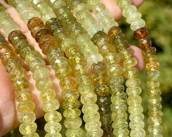 Peut inclure: Un brin de perles de pierres précieuses vertes et brunes facettées. Les perles sont petites et rondes, et elles sont enfilées sur un fil transparent. Les perles sont disposées de manière aléatoire.