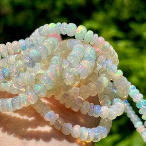 May include: A strand of white opal beads with iridescent rainbow flashes. The beads are round and have a smooth, polished finish.