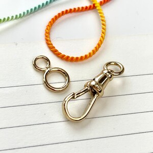 May include: Two gold-toned metal clasps. One is a simple ring, the other is a hook and loop clasp.