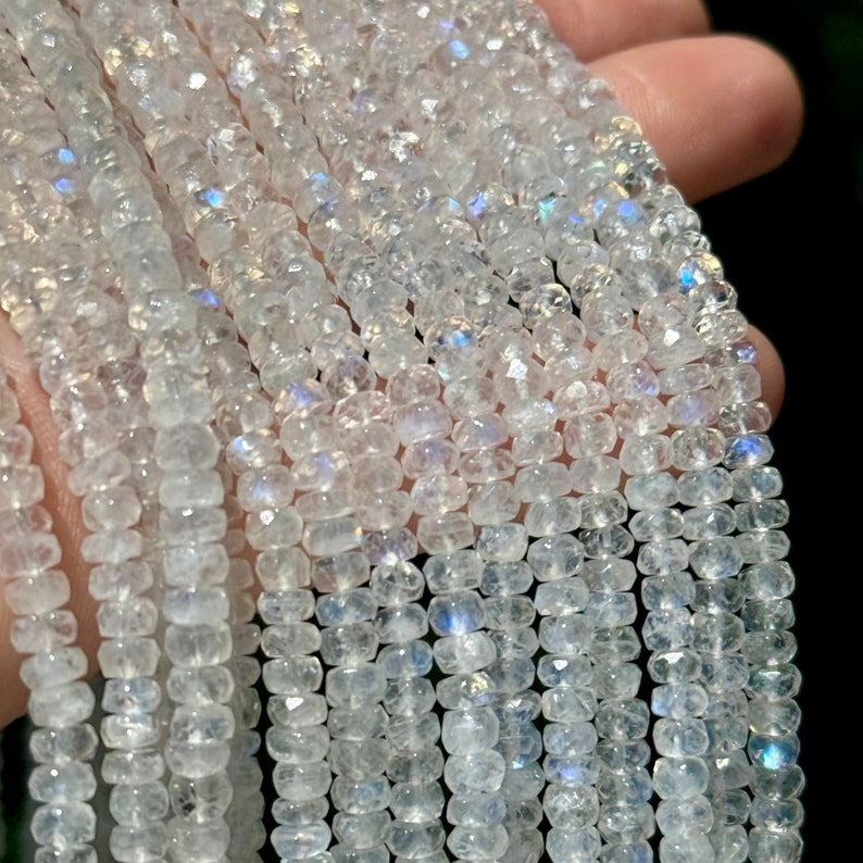 May include: A strand of white moonstone beads with iridescent shimmer. The beads are faceted and have a slightly irregular shape.