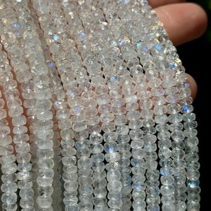 May include: A strand of white moonstone beads with iridescent shimmer. The beads are faceted and have a slightly irregular shape.
