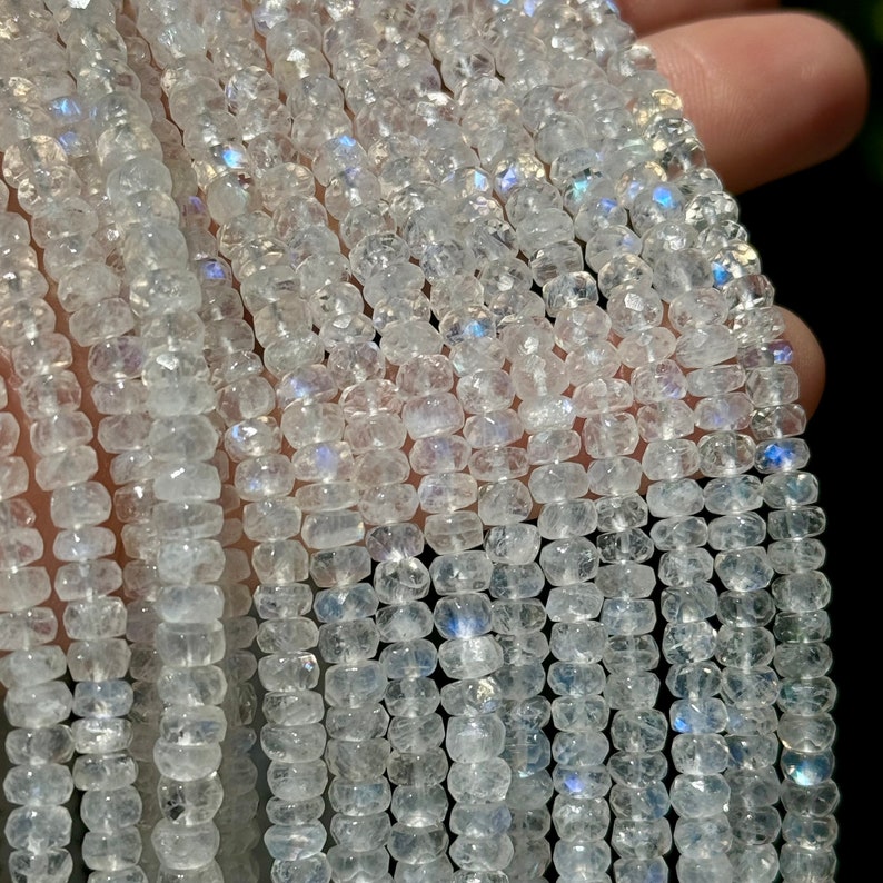 May include: A strand of white moonstone beads with iridescent shimmer. The beads are faceted and have a slightly irregular shape.