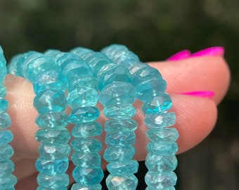 May include: A strand of light blue gemstone beads. The beads are faceted and have a slightly irregular shape. The beads are strung on a clear thread.