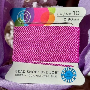 May include: A spool of pink 0.90 mm natural silk cord, labeled "Bead Snob™ Dye Job™ Griffin 100% Natural Silk" and "2M/No.10 0.90MM".