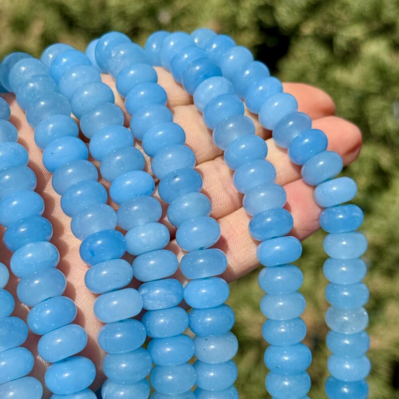 May include: A strand of light blue gemstone beads. The beads are round and smooth, and they have a slightly translucent appearance.