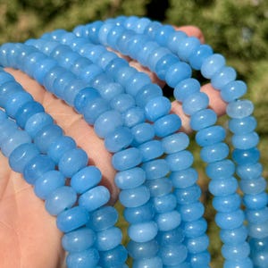 May include: A strand of light blue gemstone beads. The beads are round and smooth, and they have a slightly translucent appearance.