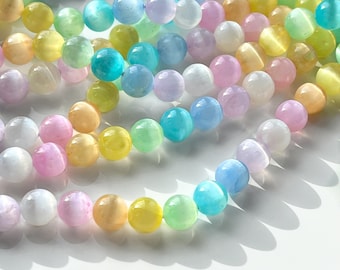 Op de afbeelding: Een streng iriserende glazen kralen in pastelkleuren, waaronder roze, geel, blauw en groen. De kralen zijn rond en hebben een gladde, glanzende afwerking.