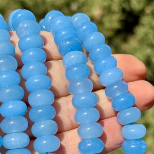 May include: A strand of light blue gemstone beads. The beads are round and smooth, and they have a slightly translucent appearance.