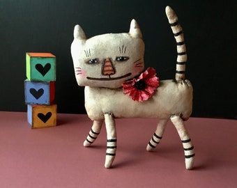 cat art fabric sculpture doll, sandy mastroni , grin, smile , a little creepy, fabric flower , white ,, standing  shelf doll,