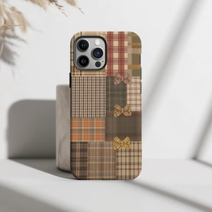 May include: A brown, tan and red plaid phone case with a patchwork design and yellow bow accents.