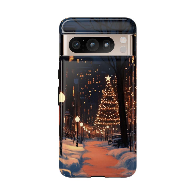 May include: A phone case featuring a winter scene with a snowy street, a lit-up Christmas tree and streetlights.