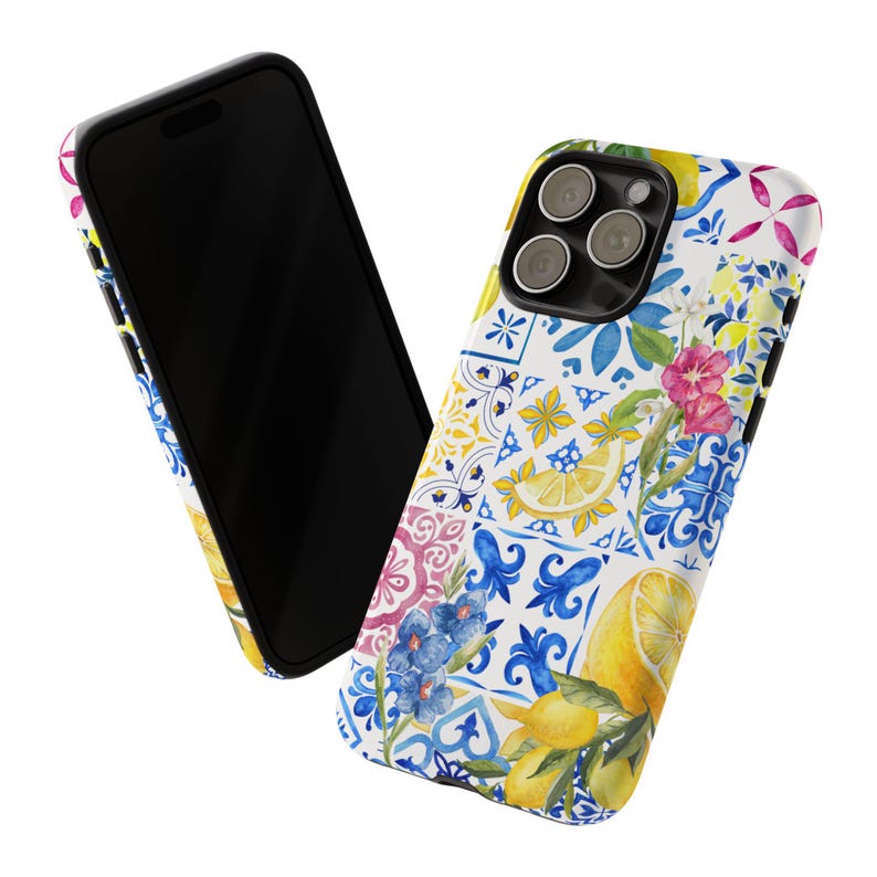 May include: A white iPhone case with a colorful pattern of blue, yellow, and pink tiles, lemons, and flowers. The case has a cutout for the camera lens.