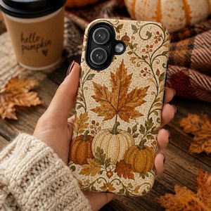 May include: A mobile phone case featuring a mosaic-style autumn design with a large central maple leaf, three pumpkins in shades of orange and cream, and intricate vine patterns. The background has a cracked texture, and the camera cutout is black.