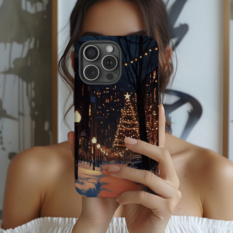 May include: A black iPhone case with a winter city scene featuring a Christmas tree and fairy lights.