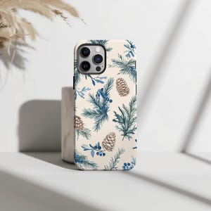May include: A white phone case with a blue and brown pine cone and evergreen pattern.