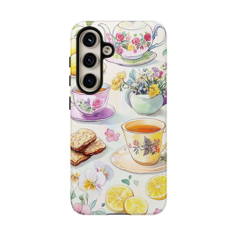K&ouml;nnte beinhalten: Eine Handyh&uuml;lle mit einem Aquarelldesign mit Teetassen, einer Teekanne, Blumen, Zitronen und Keksen. Die H&uuml;lle hat einen wei&szlig;en Hintergrund und ein Blumenmuster.