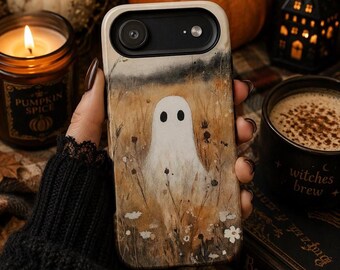 Puede incluir: Una funda de teléfono rectangular con una ilustración de un fantasma blanco en el centro de un campo de hierbas secas de color marrón dorado y pequeñas flores blancas. La parte superior es de color crema con un hueco negro para la cámara.