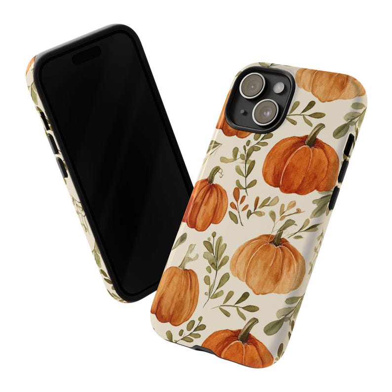May include: A phone case with a seasonal design. The case has a cream background with a pattern of orange pumpkins and green leaves. The phone case is shown with a black phone.
