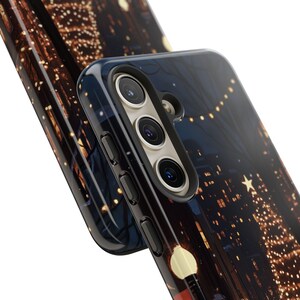 May include: A black phone case featuring a cityscape and string lights design. The case has a raised camera bump with three lenses.