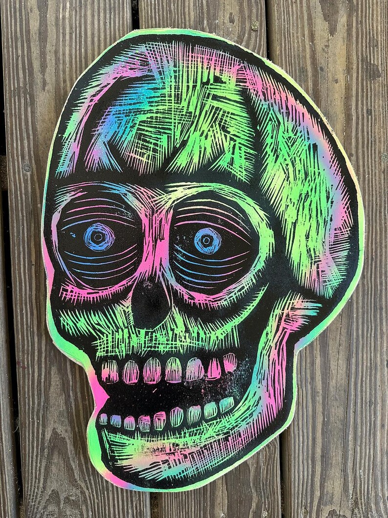Puede incluir: Una calavera negra y blanca con un efecto de pintura iridiscente verde, rosa y azul. La calavera tiene un dise&ntilde;o detallado con l&iacute;neas y sombras.