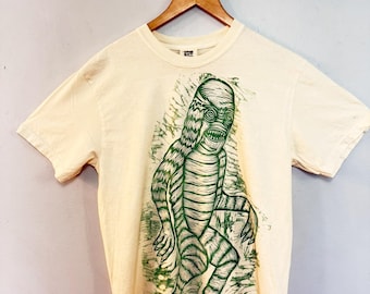 Criatura gigante impresa a mano en xilografía sobre camiseta