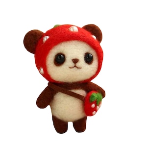 May include: A small, white panda bear wearing a red strawberry hat and carrying a brown strap bag with a green strawberry on it.