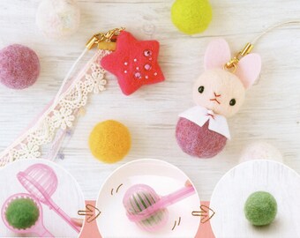 May include: A pink felt bunny charm with a white collar and pink felt star charm with rhinestones. The charms are attached to a white lace ribbon and a gold chain.