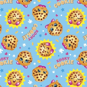 May include: A blue background with a repeating pattern of smiling chocolate chip cookies with pink bows. The cookies have chocolate chips and a white outline. The text "Kooky Cookie" is repeated throughout the pattern.