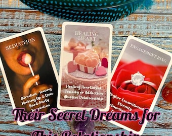 May include: Three tarot cards on a wooden surface. The cards are titled "Seduction", "Healing Heart", and "Engagement Ring". The cards feature images of a woman's lips with a lollipop, a heart-shaped box of candy, and a red rose with a diamond ring.