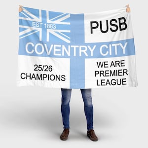 Può includere: Una bandiera bianca con una croce azzurra e un disegno Union Jack nell'angolo in alto a sinistra. La bandiera riporta le scritte "COVENTRY CITY", "25/26 CHAMPIONS" e "WE ARE PREMIER LEAGUE". La bandiera riporta anche le scritte "EST 1883" e "PUSB".