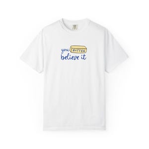 May include: White t-shirt with a blue graphic that says "you butter believe it" with a stick of butter illustration.