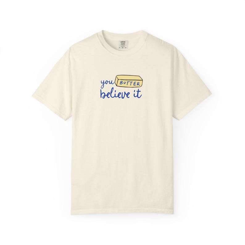 May include: A cream colored t-shirt with a blue and yellow graphic that says "you butter believe it" with a stick of butter illustration.