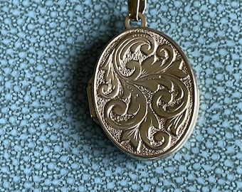 May include: A gold oval locket with an intricate floral design.