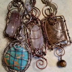 May include: A multi-strand necklace with a variety of stones and wirework. The stones include a turquoise, a clear quartz, and a brown stone. The wirework is made of copper and silver.