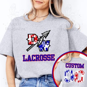 Könnte beinhalten: Graues T-Shirt mit einem rot-weiß-blauen Lacrosse-Design, auf dem "DW Lacrosse" steht. Die Rückseite des Shirts hat ein individuelles Design mit einer rot-weiß-blauen Nummer 00.
