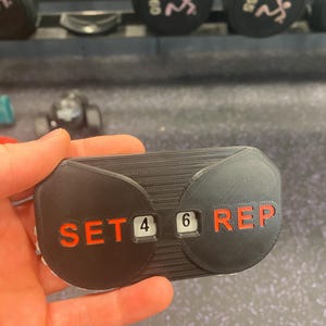 May include: A black plastic counter with red text that reads "SET 4 6 REP".