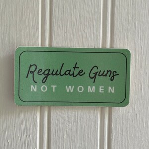 May include: A green sticker with the text "Regulate Guns Not Women" in black lettering.