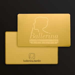 Puede incluir: Dos tarjetas de visita doradas con el texto "ballerina.berlin" y una imagen estilizada de una bailarina. La tarjeta superior tiene el texto "Ballerina BERLIN" en una fuente estilizada.